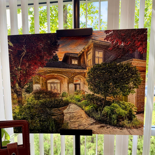 A canvas painting of a house with a stone path and greenery, displayed on a black easel in front of a window with white vertical blinds.