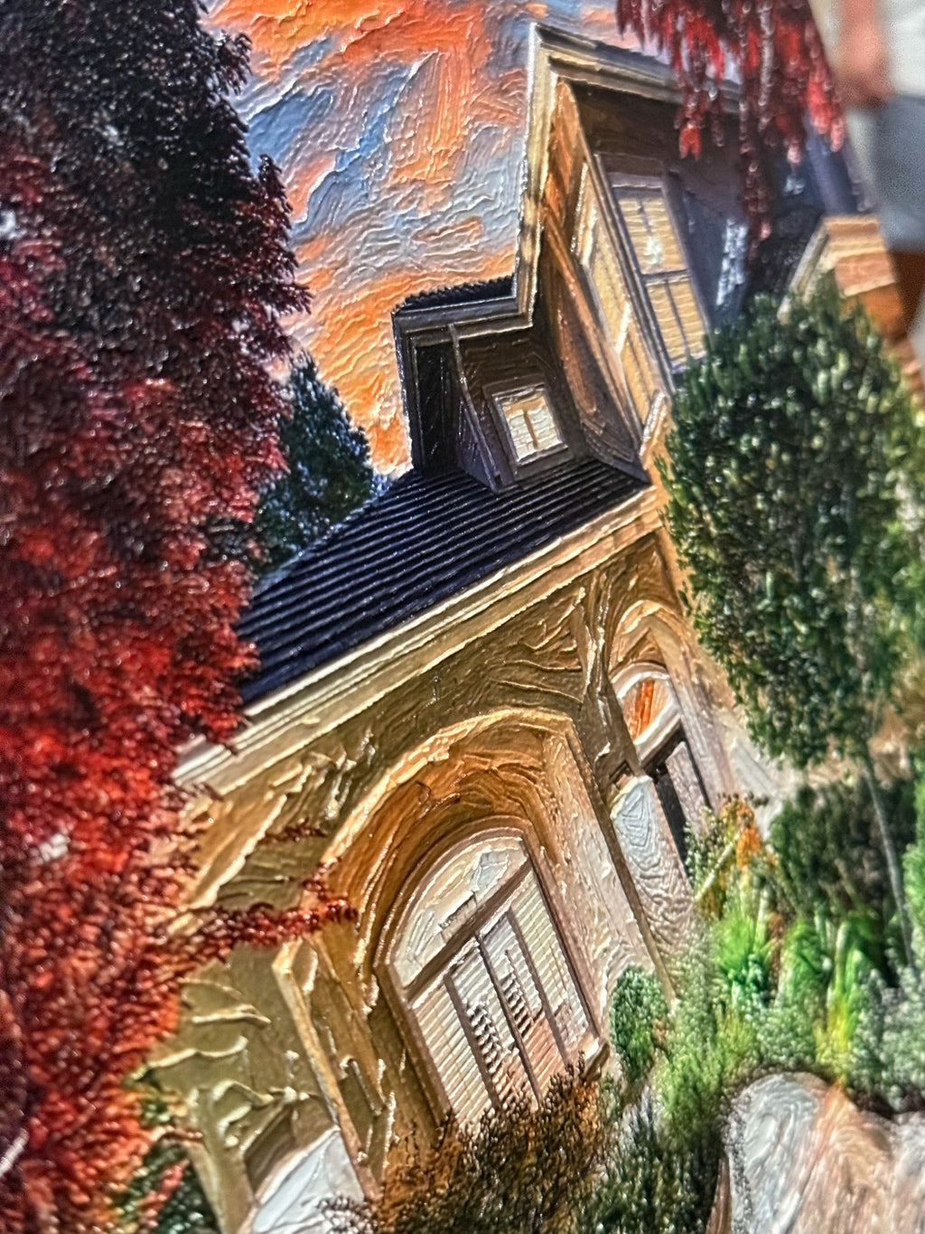 A stylized, painterly depiction of a house exterior with red autumn foliage, green shrubs, and a dramatic orange sky, shown at an angled view.